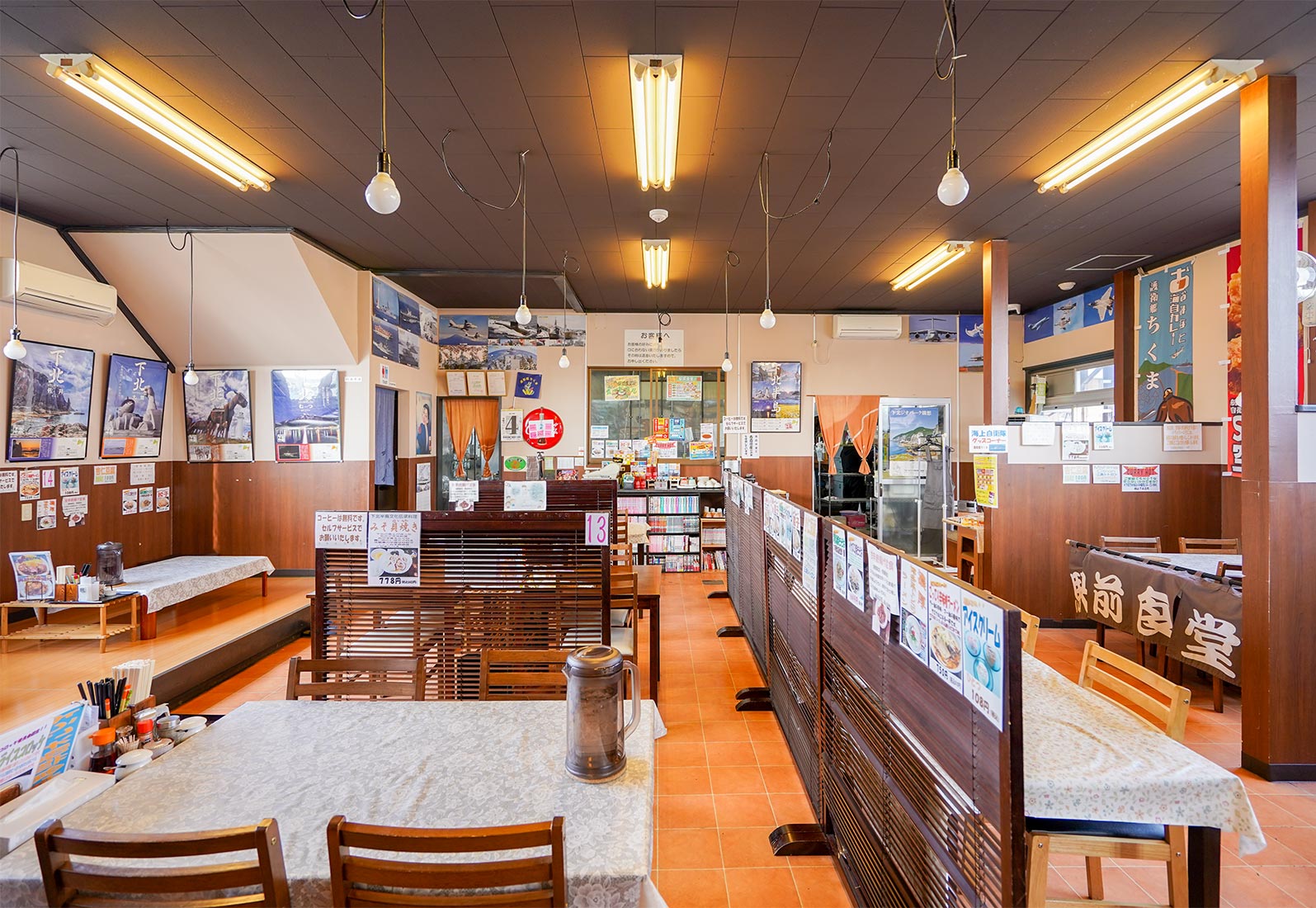 駅前食堂の店内：海自グッズが多数展示された広間とテーブル席、小上がり、暖簾